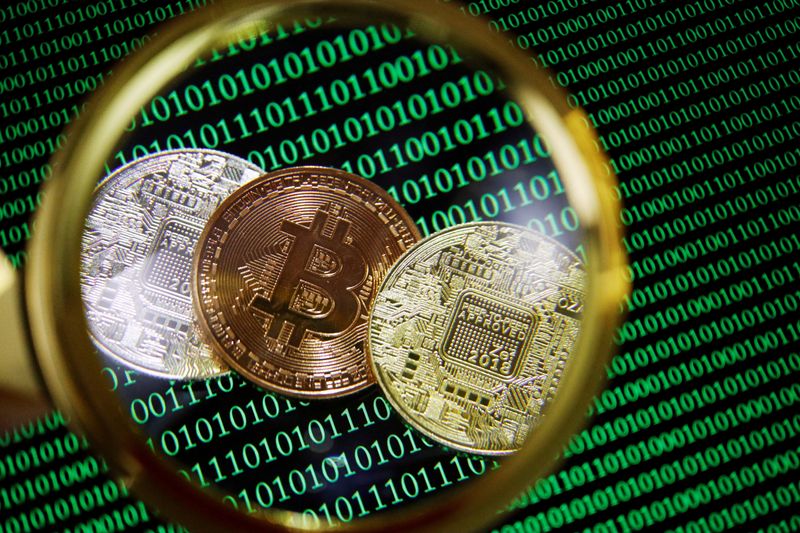 FILE PHOTO: Representations of bitcoin and other cryptocurrencies on a screen showing binary codes are seen through a magnifying glass in this illustration picture created on September 27, 2021. REUTERS/Florence Lo/Illustration/File Photo