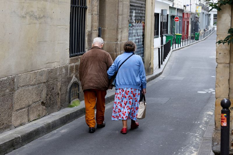 FILE PHOTO: Two older people walk arm-in-arm down a side street in Paris, France, July 14, 2024. REUTERS/Kevin Coombs/File Photo