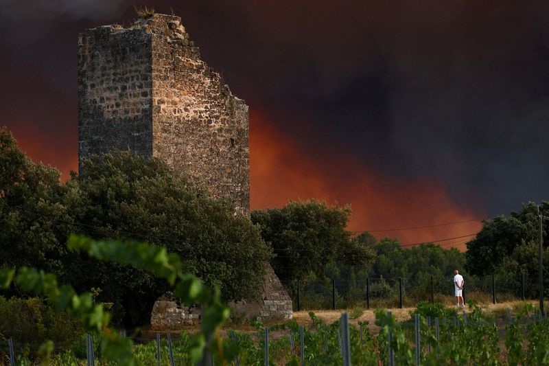 A man watches smoke drift near a ruin in the village of Cotignac, in the Var department, France, following a wildfire, July 21, 2026. REUTERS/Manon Cruz