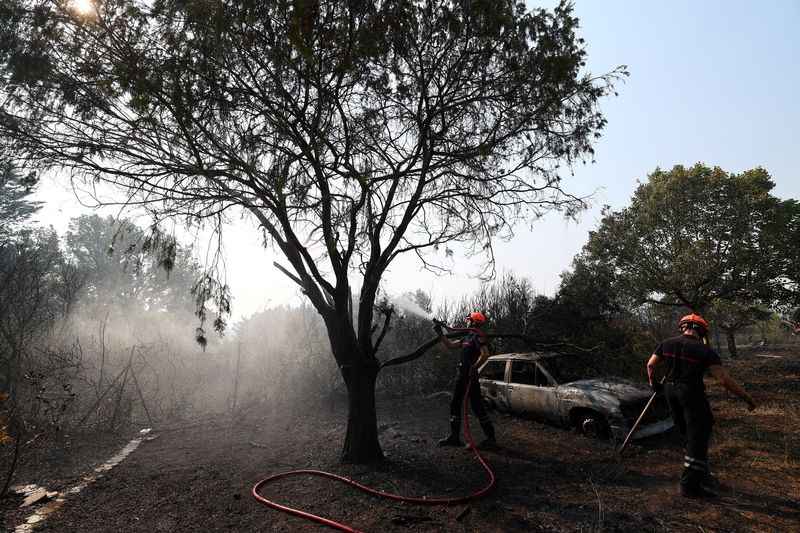 French firefighters spray water during mop-up operations near a burnt house and a burnt car in an area affected by a wildfire in Cotignac, in the Var department, as drought conditions worsen following a heatwave and water shortages across much of France, July 22, 2026. REUTERS/Manon Cruz