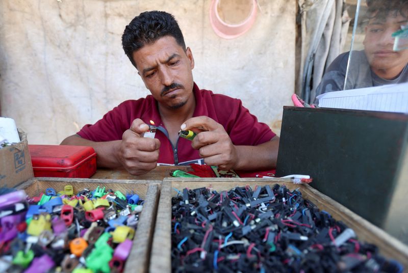 Palestinian lighter repairman Hassan Abu Latifa ignites a repaired lighter at his kiosk, amid shortages of lighters and cooking gas, in Khan Younis, in the southern Gaza Strip, July 21, 2026. REUTERS/Ramadan Abed