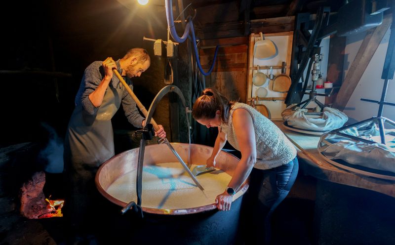 Traditional Gruyere cheese producer Alexandre Murith and his wife Charline cut curds in a copper vat during cheesemaking on the Tsermon mountain pasture, as Switzerland faces new 12.5% U.S. tariffs imposed by the Trump administration, in Moleson-sur-Gruyeres, Switzerland, July 24, 2026. REUTERS/Denis Balibouse