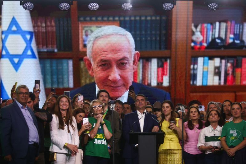 Brazilian Senator Flavio Bolsonaro, who is to be announced as candidate for Brazil's presidential elections, stands in front of a screen showing a pre-recorded message from Israeli Prime Minister Benjamin Netanyahu during the national convention of the Liberal Party (PL) in Sao Paulo, Brazil, July 25, 2026. REUTERS/Jean Carniel