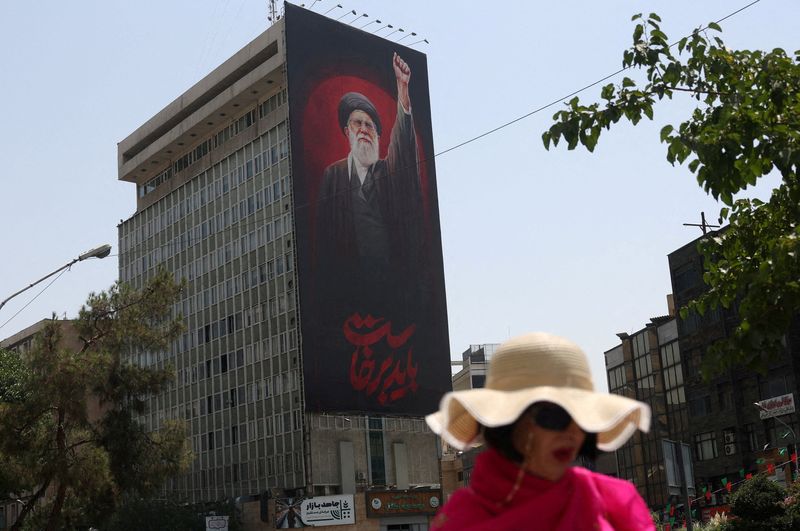 A woman walks by a billboard depicting Iran's late Supreme Leader Ayatollah Ali Khamenei, on a street in Tehran, Iran, July 21, 2026.  Majid Asgaripour/WANA (West Asia News Agency) via REUTERS