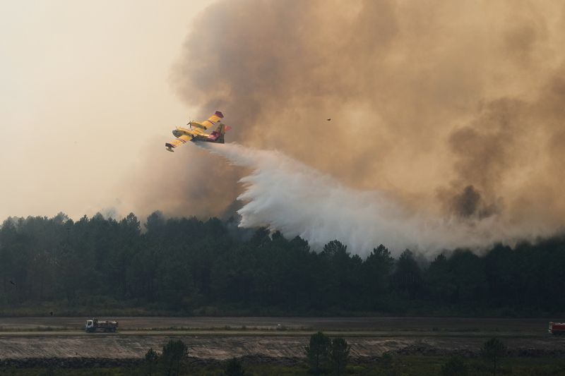 A plane drops water on a fire near Ares, during wildfires in the area of southwestern France, Tuesday, July 28, 2026. Baz Ratner/Pool via REUTERS