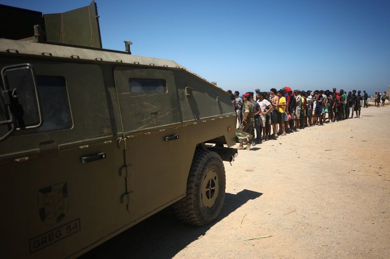 Migrants wait in line to receive water from the Spanish military, following mass crossings of migrants on foot and by sea from Morocco into Spanish territory, in Ceuta, Spain, August 2, 2026. REUTERS/Pedro Nunes