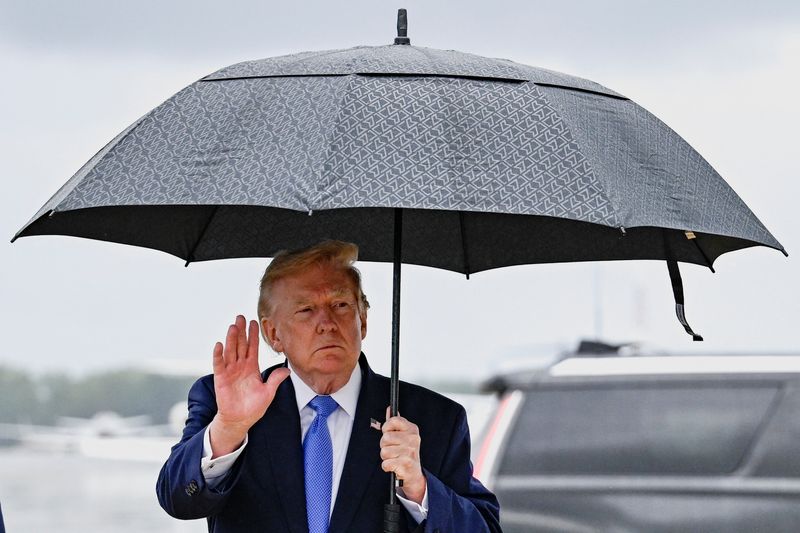 U.S. President Donald Trump gestures as he holds an umbrella after disembarking Air Force One at Joint Base Andrews, in Maryland, U.S., August 2, 2026. REUTERS/Daniel Heuer