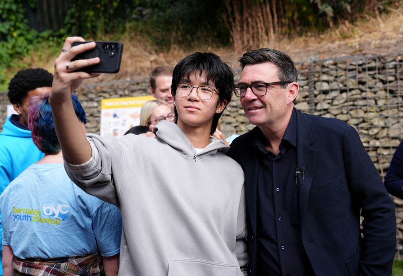 FILE PHOTO: Britain's Prime Minister Andy Burnham has a selfie taken during a visit to a family centre in Sheffield, South Yorkshire, for the launch of the biggest transfer of power from Westminster in a generation, which will allow English mayors to keep a share of the taxes collected in their area, giving communities greater control over the decisions that shape jobs, transport, housing and public services. July 31, 2026.    Annabel Lee-Ellis/Pool via REUTERS/File Photo