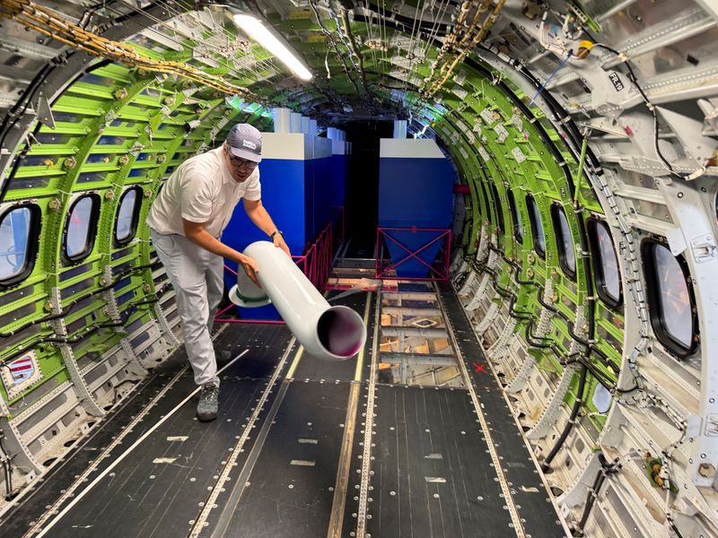 Jonathan Beck, head of overall aircraft design at Positive Aviation, handles a component of a water-scooping system on a converted ATR-72 firefighting demonstrator, in Toulouse, France, July 31, 2026. REUTERS/Tim Hepher