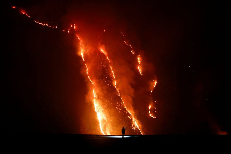 A person observes flames during wildfires on a hill slope in Bromo Tengger Semeru National Park in Probolinggo, East Java province, Indonesia, August 9, 2026. REUTERS/Dipta Wahyu