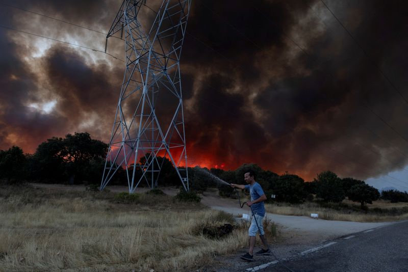 FILE PHOTO: A resident sprays water to wet the grass in the hope that this will stop an advancing wildfire near Formariz in Zamora province, Spain, July 29, 2026. REUTERS/Umit Bektas/File Photo