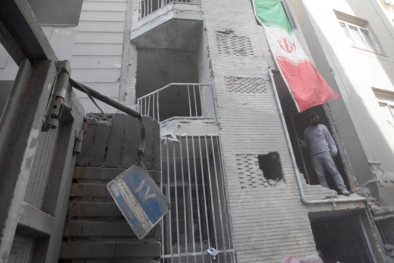 A picture taken by Yalda Moaiery, who received a 15 year prison sentence for her work as a journalist in Iran, shows a man looking out of a damaged building at the site of a strike carried out during the 40-day U.S.-Israeli conflict with Iran, in Tehran, Iran, March-April 2026. At the centre of Moaiery's case are images she took during the U.S.-Israeli airstrikes in Iran. Yalda Moaiery/Handout via REUTERS  