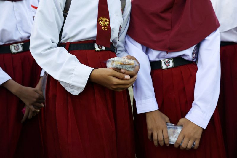Students hold chicken rice in a plastic container at an elementary school in the fishing village of Torosiaje, Gorontalo province, Indonesia, July 27, 2026. REUTERS/Ajeng Dinar Ulfiana