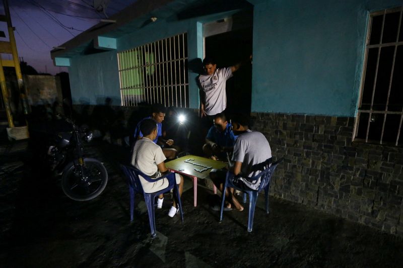 People play a game of dominoes by the light of a cell phone during a blackout, as Venezuelans face increasing power cuts due to the country's deteriorated grid, in Valencia, Venezuela May 8, 2026. REUTERS/Juan Carlos Hernandez