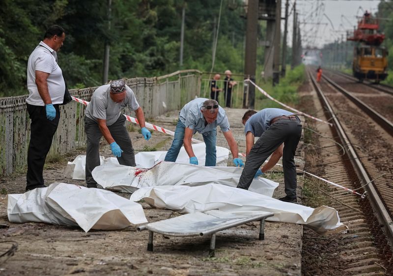 Workers place bodies of residents into body bags after they were killed at a railway station, the site of Russian air strike, amid Russia's attack on Ukraine, in Kyiv region, Ukraine August 5, 2026. REUTERS/Stringer
