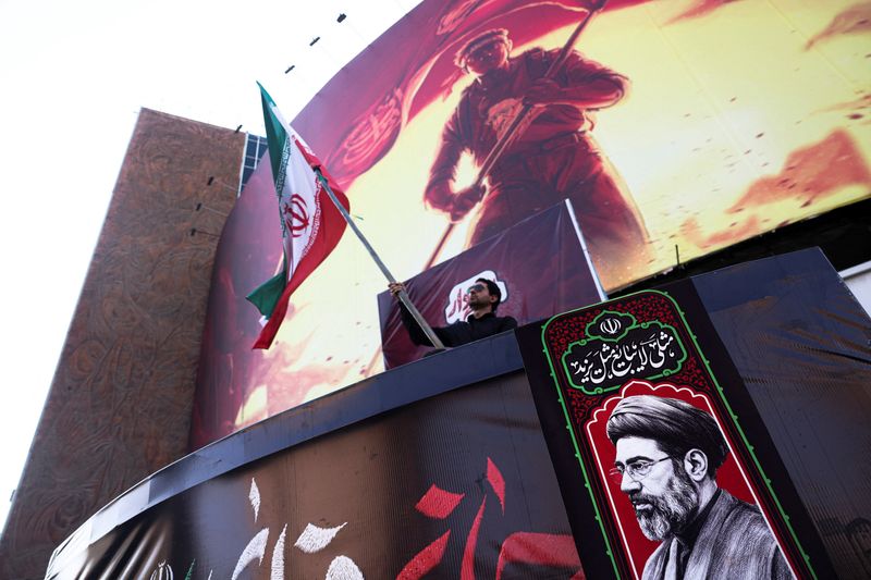 A man holds an Iranian flag, next to a picture of Iran's Supreme Leader Mojtaba Khamenei, in Tehran, Iran, August 13, 2026. Majid Asgaripour/WANA (West Asia News Agency) via REUTERS