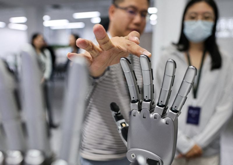 FILE PHOTO: A man touches a robotic hand displayed at the demonstration area at the office of Linkerbot, in Beijing, China, April 27, 2026. REUTERS/Maxim Shemetov/File Photo