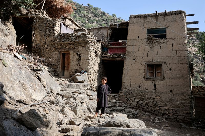 FILE PHOTO: A boy stands in front of houses damaged by a deadly earthquake that struck Afghanistan's Kunar and Nangarhar provinces, at Masud village in Nurgal district, Kunar province, Afghanistan, September 4, 2025. REUTERS/Sayed Hassib/File Photo