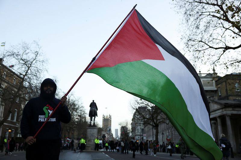 FILE PHOTO: A person holds a Palestinian flag during a protest in solidarity with Palestinians in Gaza, amid the ongoing conflict between Israel and the Palestinian Islamist group Hamas, in London, Britain, December 9, 2023. REUTERS/Hollie Adams/File Photo