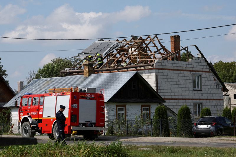 FILE PHOTO: A police officer stands below as firefighters work on the destroyed roof of a house, after Russian drones violated Polish airspace during an attack on Ukraine, with some being shot down by Poland with the backing from its NATO allies, in Wyryki-Wola, Lublin Voivodeship, Poland, September 10, 2025. REUTERS/Kacper Pempel/File Photo