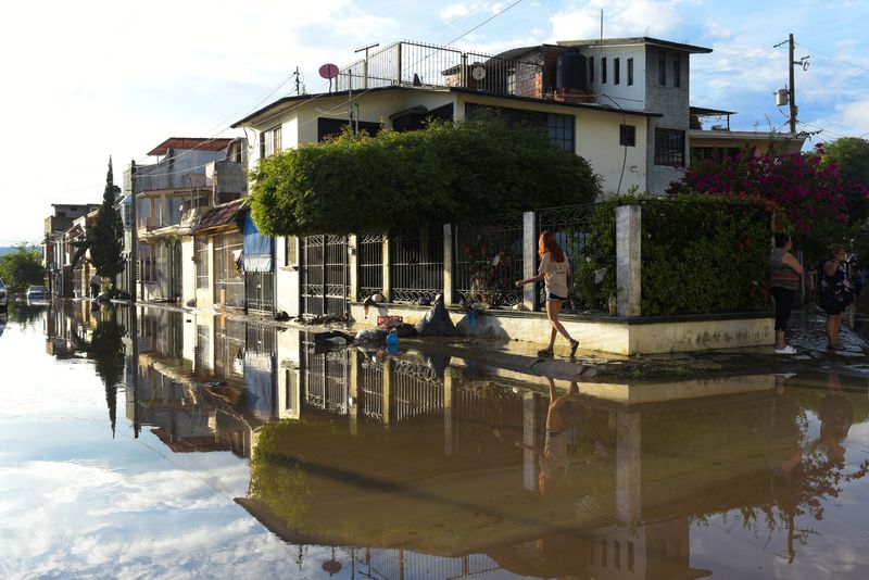 A woman walks near a flooded street after torrential rains that overflowed rivers, causing flooding in Poza Rica, Veracruz state, Mexico October 10, 2025. REUTERS/Rolando Ramos