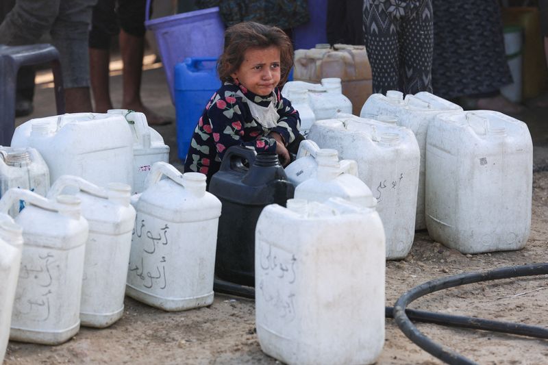 A Palestinian child among water containers, amid a ceasefire between Israel and Hamas, in Khan Younis, southern Gaza Strip, October 16, 2025. REUTERS/Ramadan Abed
