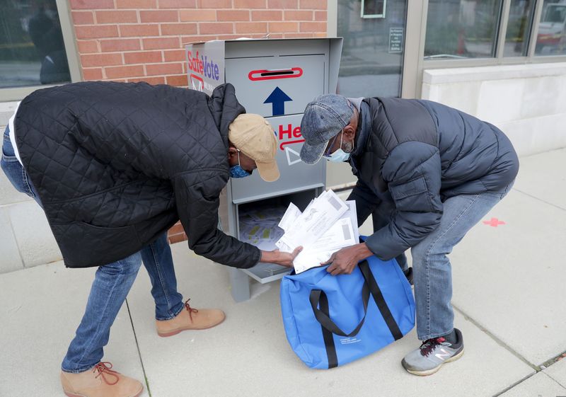 City of Milwaukee employees, Steven Coleman, left, and Larry Ponder remove ballots from a ballot drop box on the sidewalk outside the Washington Park Library on in Milwaukee October 3, 2020. Voters will now have to put their own ballots in the mail.