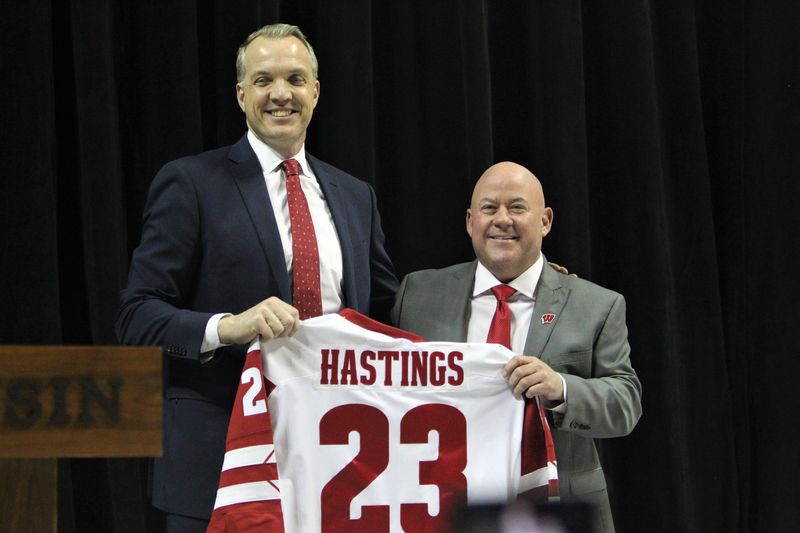 Wisconsin director Chris McIntosh (left) and men's hockey coach Mike Hastings' pose for a picture after Hastings' receives a Badgers jersey during his introductory press conference Monday April 3, 2023 at the Kohl Center in Madison, Wis.