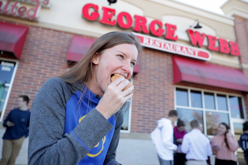 Lauren Wysocki of Pewaukee takes a bite out of her free hamburger at the George Webb Restaurant in Brookfield, where she was with her mother, Sandy Wysocki. George Webb Restaurants across the state handed out free hamburgers on Thursday, delivering on the promise it made if the Brewers won 12 games in a row. The restaurant allowed one burger per customer.