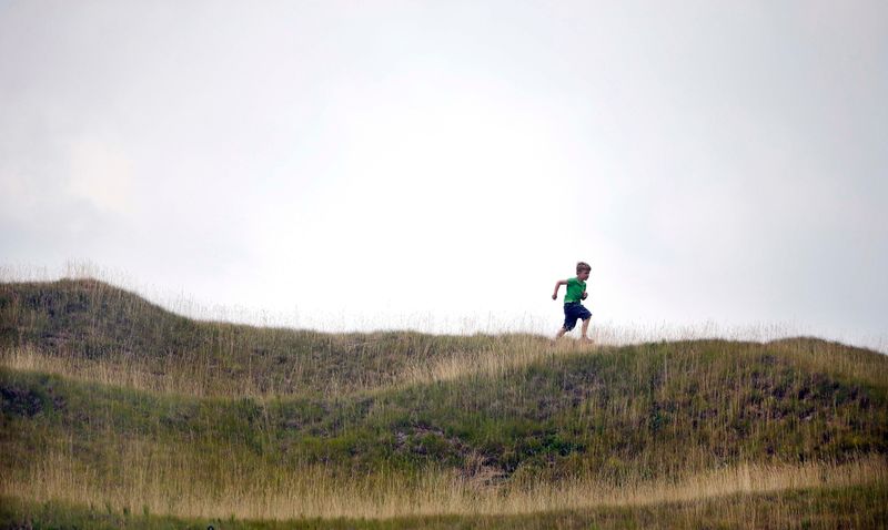 A boy runs across a hill top as rains approach to interrupt a practice  round for the PGA Championship at Whistling Straits in Haven.