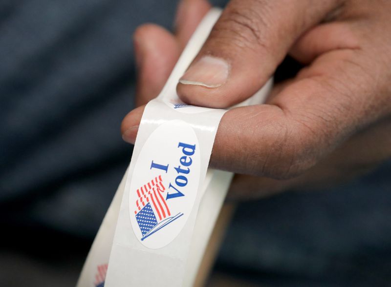 Poll worker Charles Hawkins holds "I Voted" stickers at the Mary Ryan Boys & Girls Club of Greater Milwaukee on North Sherman Boulevard in Milwaukee on Tuesday, Feb. 18, 2020.