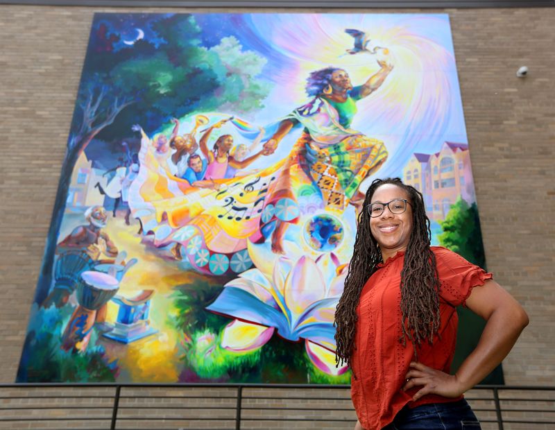 Milwaukee muralist Tia Richardson stands in front of one of her many Milwaukee-area murals on May 31, 2021. She created this one, "The Rebirthing of the Earth Mother," at 2215 N. Phillips Ave. in 2018. Richardson typically involves community members in painting the murals she designs as a way to promote unity and healing.