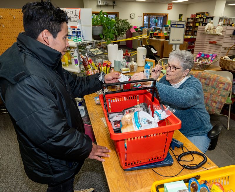 Kay Robles, the site manager of the Community Space in Whitewater, hands Edwin-Josue Pres-Ruiz of Nicaragua a card with the hours the facility is open. Pres-Ruiz, a father of two young daughters, came to Whitewater to work and send money home to his family.