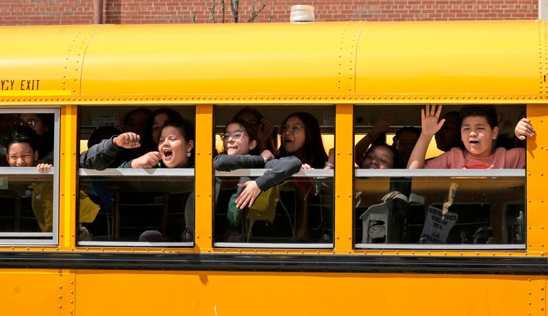 Children in a school bus cheer on parade marchers marching in the Annual May Day March in Milwaukee on Wednesday, May 1, 2024.
