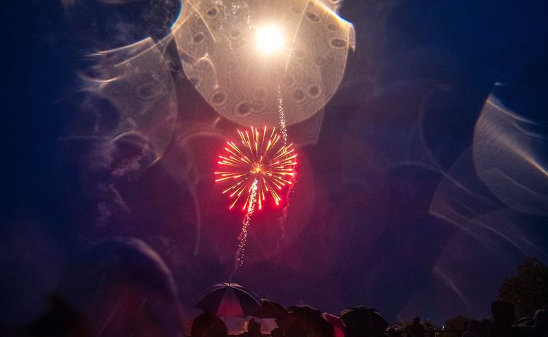 Wisconsin Rapids holds their annual Independence Day fireworks through the heavy rain over the Wisconsin River in Wisconsin Rapids, Wis. on Thursday, July 4, 2024. Spectators gathered closely under tarps, trees and umbrellas to avoid what rain they could while still finding which ever spaces they could in Veterans Memorial Park or on the West Grand Avenue Bridge to catch sight of the explosive show.