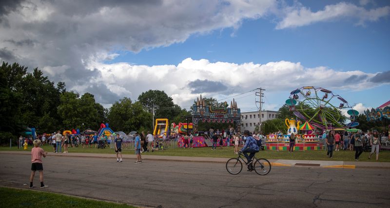 Patches of sun shine through as rain pours down on the Riverfront Rendezvous in Stevens Point , Wis. on Friday, July 5, 2024. Despite the sporadic downpours music filled the air and carnival rides kept running.