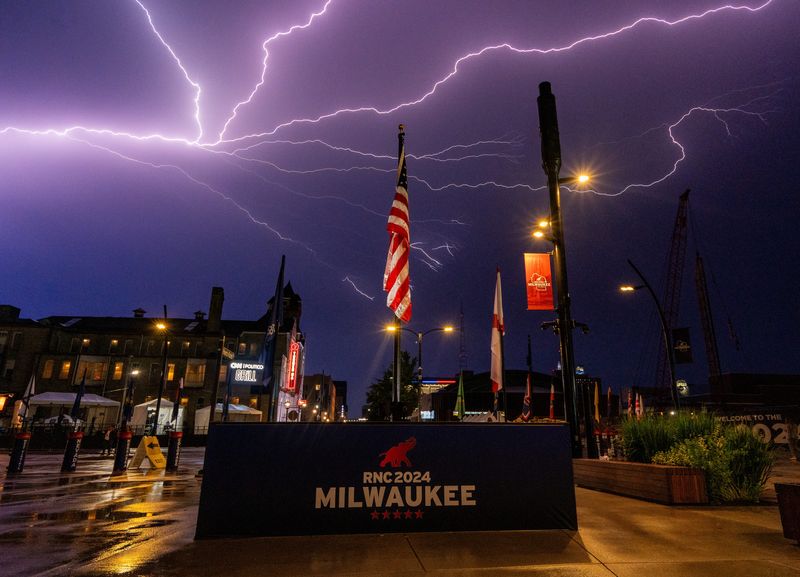 Lightning strikes behind a RNC 2024 Milwaukee flag display on the opening day of the Republican National Convention on Monday July 15, 2024 in Milwaukee, Wis.