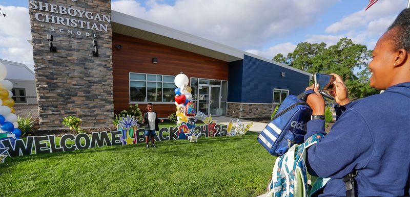 Beatrice Boateng, right, snaps a photo of her son Raymond, 5, the first day of classes at Sheboygan Christian, Tuesday, August 20, 2024, in Sheboygan, Wis.