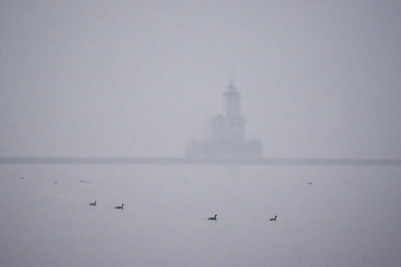 The breakwater lighthouse is obscured as smoke from the Canadian wildfires continues to linger in the morning air on June 30, 2023.