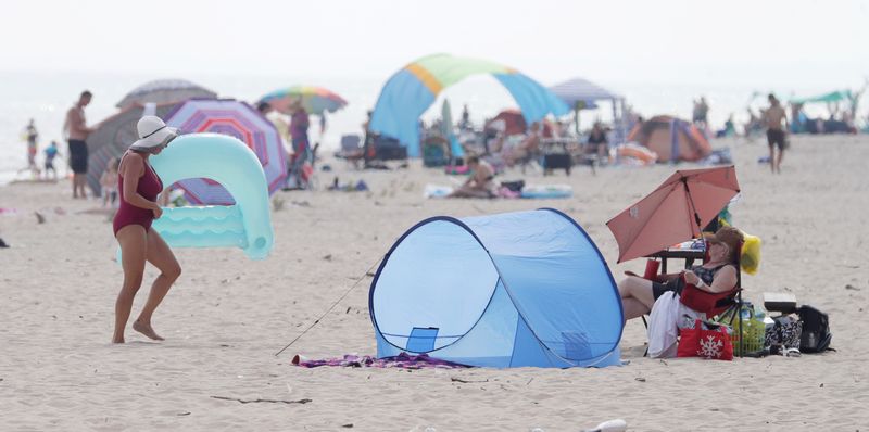 People relax and cool off along Lake Michigan at Kohler Andrae State Park, Monday, August 26, 2024, in Sheboygan, Wis.