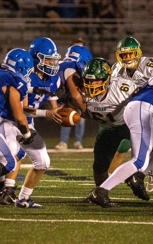 Edgar Wildcat senior Fletcher Weiland (61) looks at the ball as Assumption Royal sophomore Braxten Steinert (3) passes the ball to Assumption Royal sophomore Wylie Cornwell (7) during the game at Rapids Area Sports Complex on Friday, Sept. 27, 2024. Edgar won 48-0.