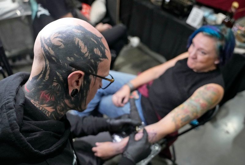 Jimbo Ermilio, with The Brook Tattoo, out of Hastings, Minn., tattoos Alicia Larson, of Black Creek at the Milwaukee Tattoo Arts Festival at the Baird Center in Milwaukee on Friday, Oct. 4, 2024. The event, which includes body artists, merchandise, and entertainers continues from 11 a.m. to 11 p.m. Oct. 5 and 11 a.m. to 8 p.m. Oct. 6. Admission is $20 for a daily pass, $40 for a three-day pass and free for kids younger than 12.