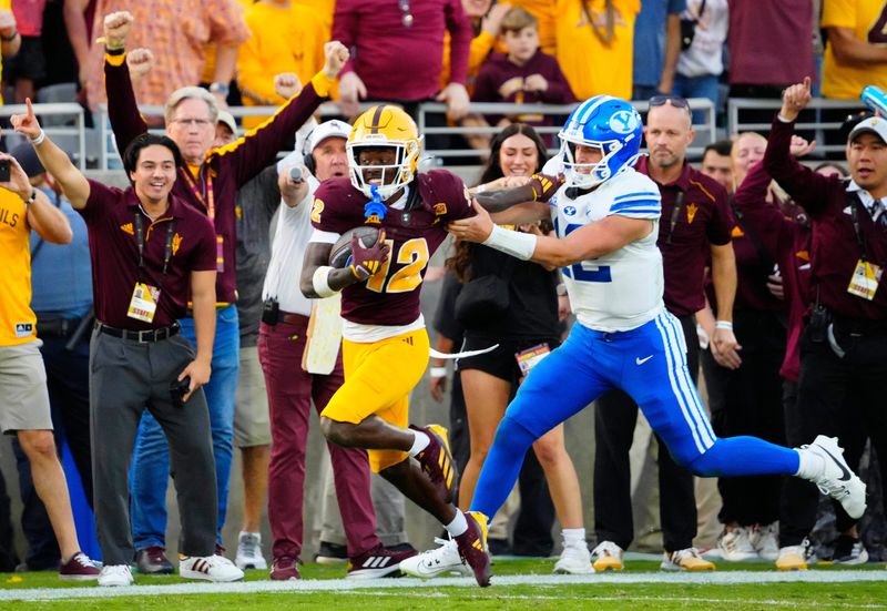 BYU quarterback Jake Retzlaff (12) tackles Arizona State defensive back Javan Robinson (12) as he returns an interception during the second half at Mountain America Stadium in Tempe on Nov. 23, 2024.