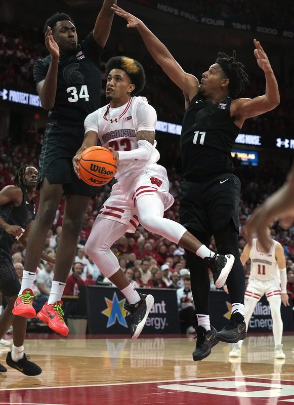 Wisconsin guard Chucky Hepburn (23) fills to score on Michigan State forward Xavier Booker (34) and guard A.J. Hoggard (11) during the second half of their game Friday, January 26, 2024, at the Kohl Center in Madison, Wisconsin. Wisconsin beat Michigan State 81-66.