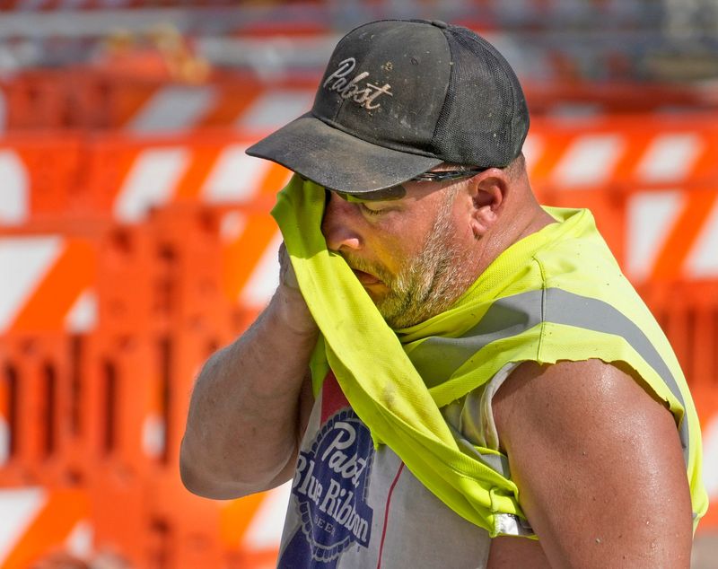 Jeff Nerby, with Arrow-Crete Construction, wipes away the sweat on a hot and humid day while working on a project involving a bump out for a bike path car the corner of East Well Street in North Milwaukee Street in Milwaukee on Monday, June 17, 2024.