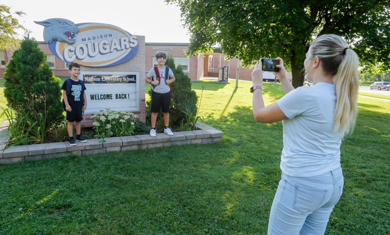 Meii Shakreta, right, snaps a photo of her sons Anaur, 6, and Viar, 9, before their first day of school Aug. 30, 2022, at Madison Elementary School in Manitowoc, Wis.