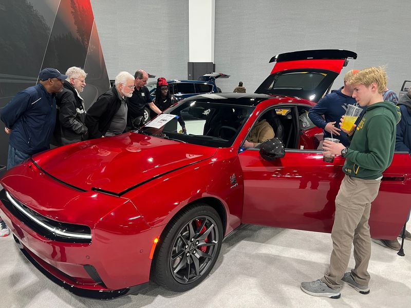 Car fans at the Milwaukee Auto Show gather around a Dodge Charger Daytona, a two-door electric muscle car, on Friday, Feb. 28, 2025. Sales of electric vehicles, chargers and solar panels are increasing as federal tax credits end.
