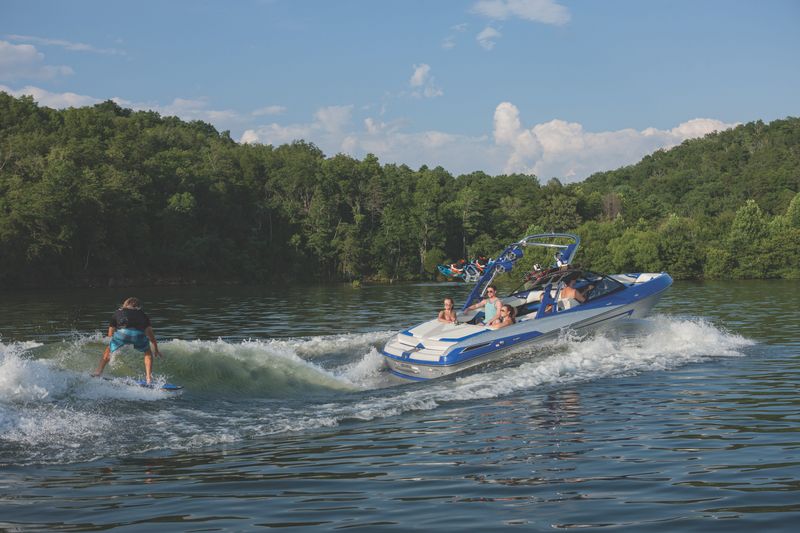 A wake surfer rides the wave behind a wake boat.