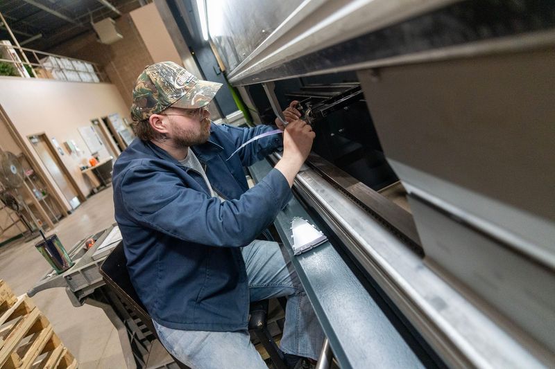 John Mackay, a fabricator, works on bending metal on a newer press brake machine at Reflective Concepts, a custom metal fabricator in Kenosha on June 5, 2025.