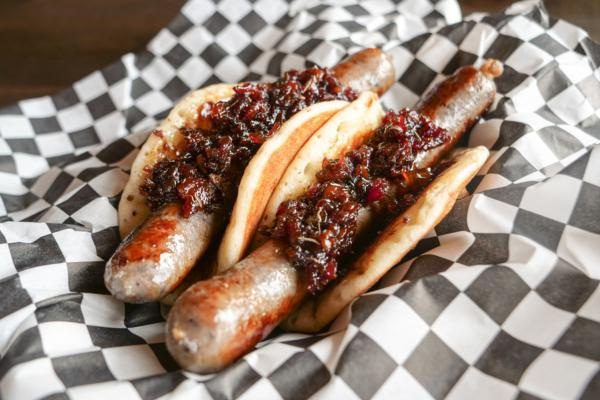 Milwaukee Brat House's Blueberry Breakfast Bratwurst — a Usinger's blueberry-infused brat topped with house-made bourbon bacon jam in a pancake "bun" — is a 2025 Wisconsin State Fair Sporkies and Drinkies Finalist.